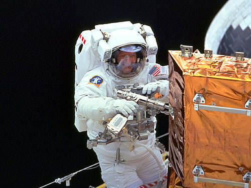 A space shuttle spacewalker with a drill specially fitted for space.